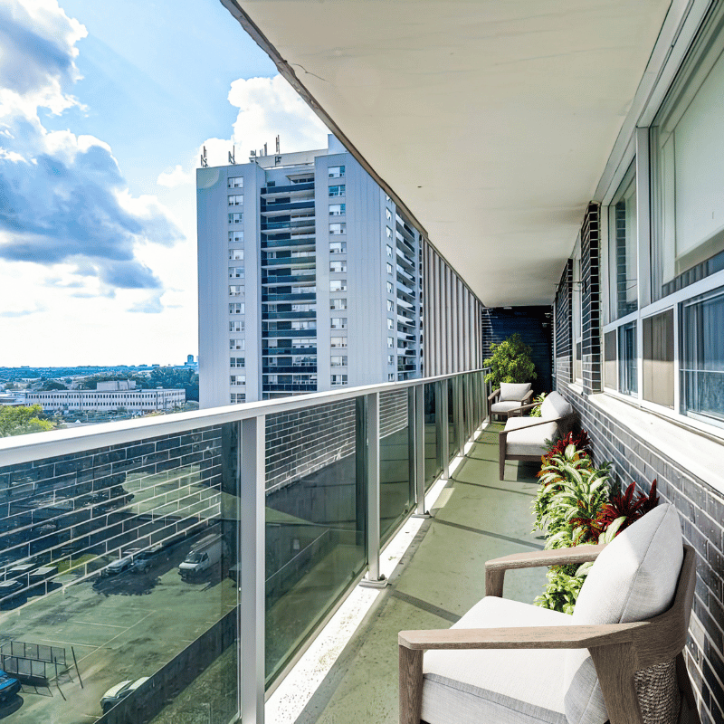 Balcony with greenery and chairs, and a treetop view.